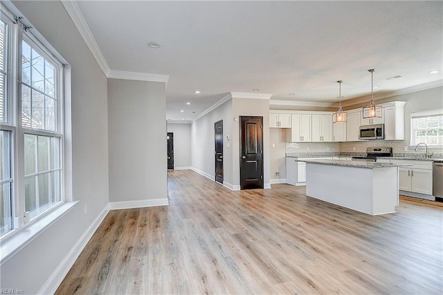 kitchen with light wood-style flooring, tasteful backsplash, white cabinetry, stainless steel appliances, and baseboards