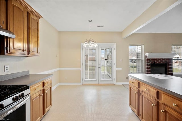 kitchen with brown cabinetry, gas stove, and baseboards