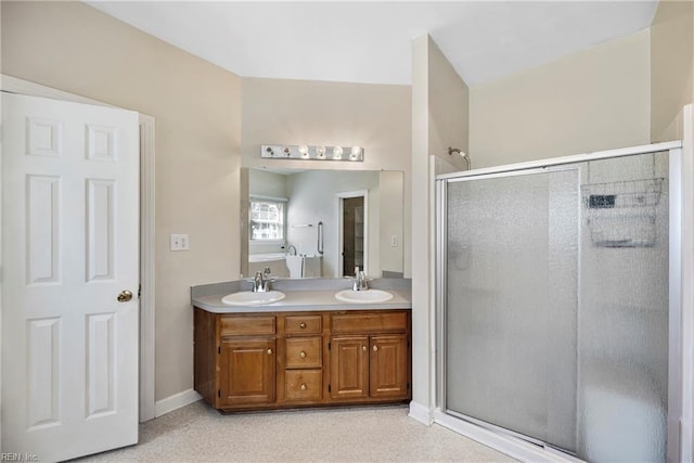 full bathroom featuring double vanity, a shower stall, baseboards, and a sink