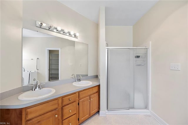 bathroom featuring double vanity, a stall shower, and a sink