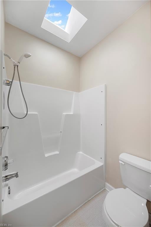 bathroom featuring bathtub / shower combination, a skylight, toilet, and baseboards