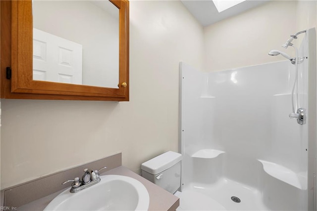 bathroom with toilet, a skylight, vanity, and walk in shower