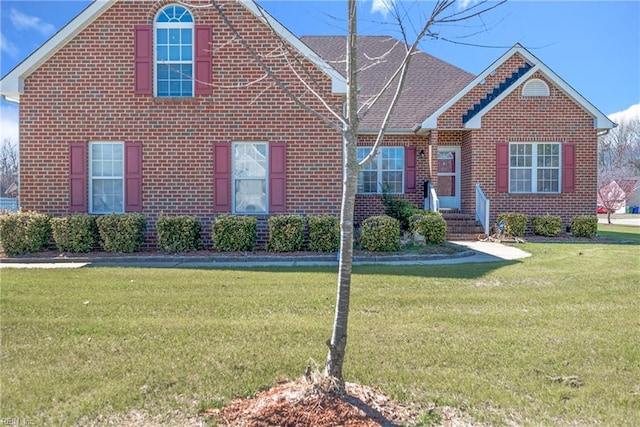 view of front facade featuring a front yard, brick siding, and a shingled roof