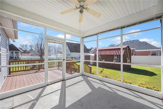 unfurnished sunroom with a residential view and a ceiling fan