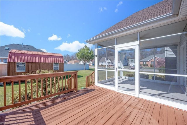 wooden deck with fence, a lawn, an outbuilding, and a sunroom