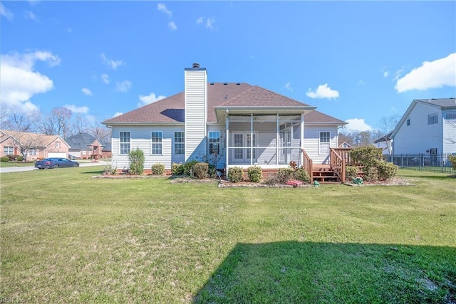 rear view of house with fence, a lawn, a chimney, and a sunroom