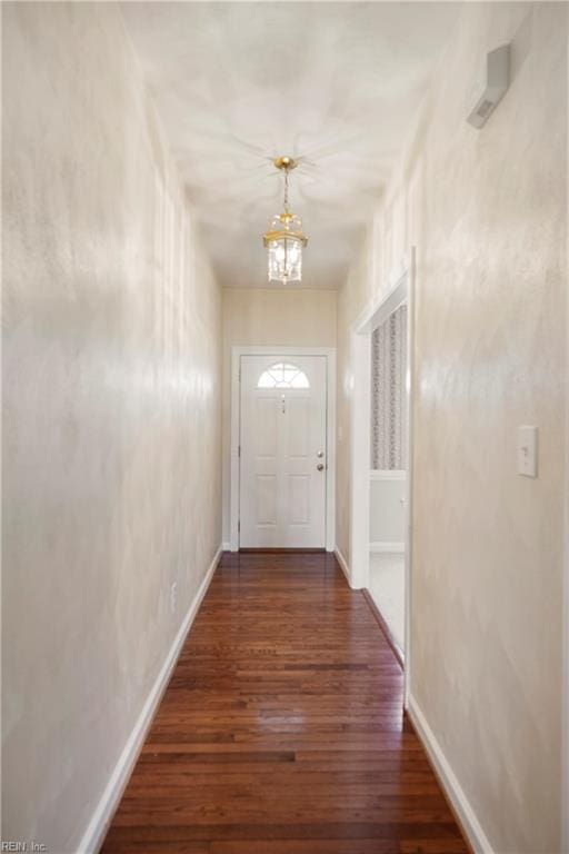 doorway featuring a chandelier, baseboards, and hardwood / wood-style floors