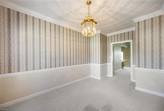 empty room with baseboards, carpet floors, wallpapered walls, ornamental molding, and a chandelier