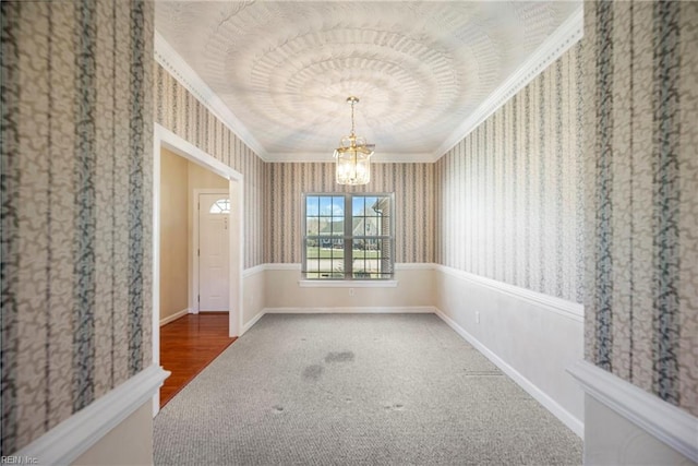 spare room featuring baseboards, wallpapered walls, ornamental molding, carpet flooring, and a chandelier