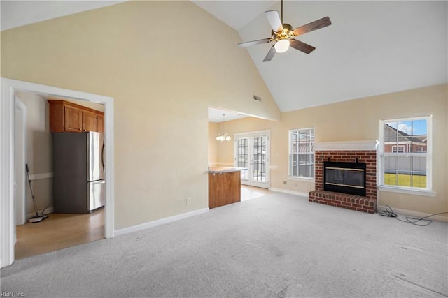 unfurnished living room with a ceiling fan, a brick fireplace, a healthy amount of sunlight, and light carpet