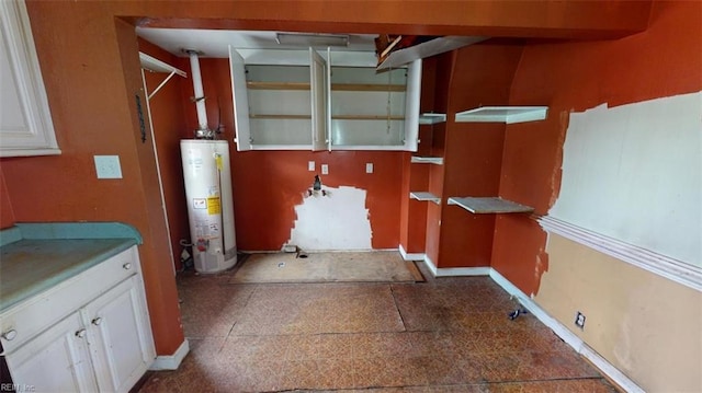 interior space featuring gas water heater, white cabinets, and baseboards