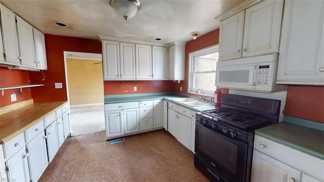 kitchen with white cabinetry, black gas range, white microwave, and a sink