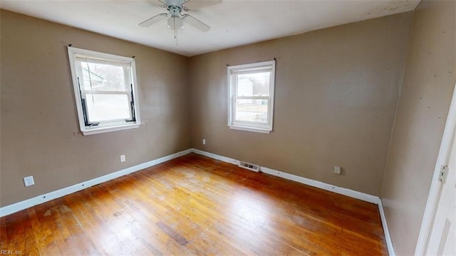 unfurnished room featuring ceiling fan, visible vents, baseboards, and hardwood / wood-style floors