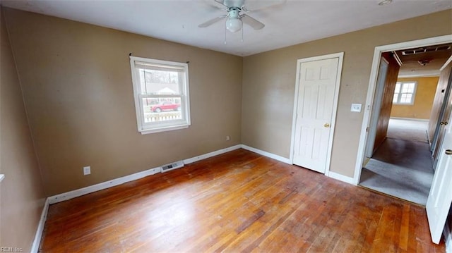 unfurnished bedroom featuring visible vents, light wood-style floors, baseboards, attic access, and ceiling fan