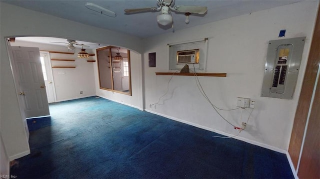 carpeted empty room featuring electric panel, baseboards, arched walkways, and a ceiling fan