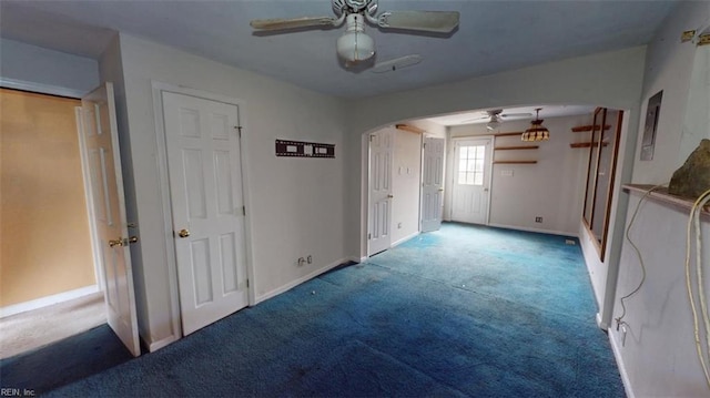 unfurnished bedroom featuring baseboards, arched walkways, a ceiling fan, and carpet flooring