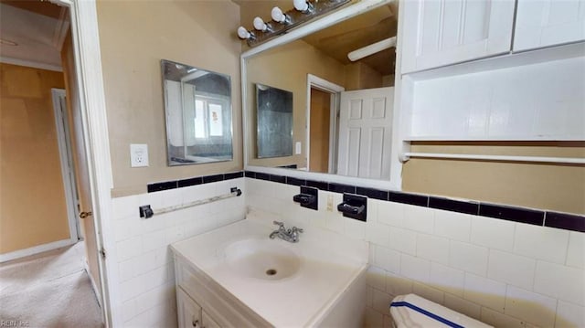 half bath featuring vanity and tile walls