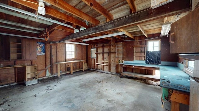 misc room with a wealth of natural light, a workshop area, concrete floors, and electric panel