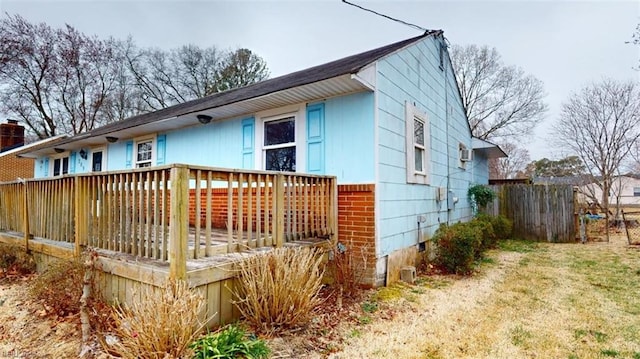 ranch-style house with a front lawn, a deck, and fence