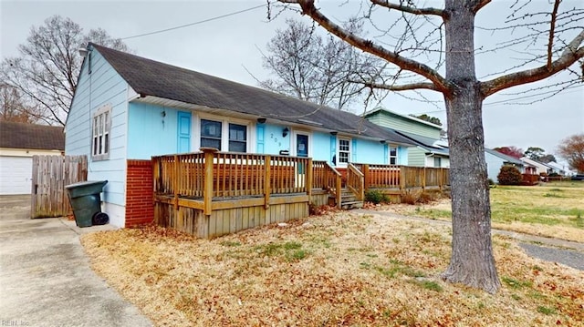 view of front facade with a garage, a deck, and a shingled roof