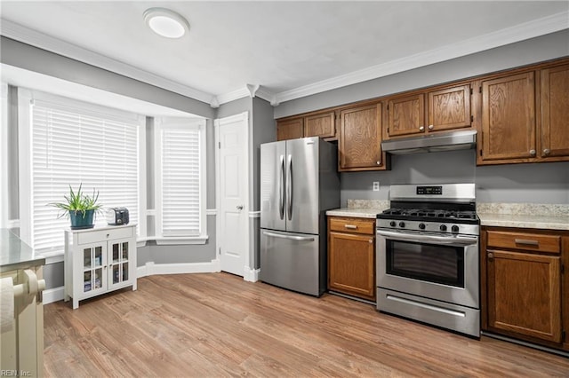 kitchen with under cabinet range hood, appliances with stainless steel finishes, ornamental molding, and light wood finished floors