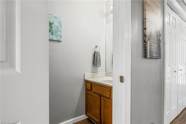 bathroom featuring baseboards, wood finished floors, and vanity