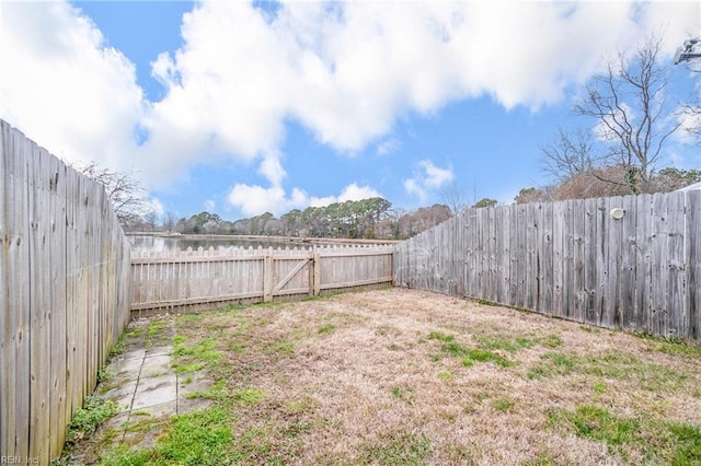 view of yard with a fenced backyard and a water view