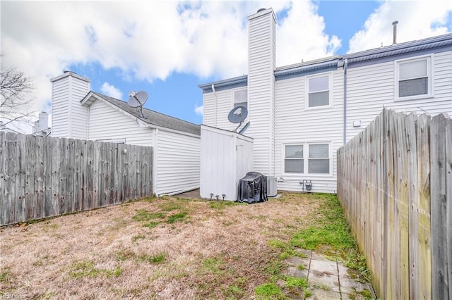 back of property with a fenced backyard and a chimney