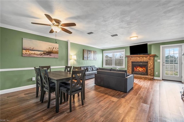 dining space with wood finished floors, crown molding, a healthy amount of sunlight, and visible vents