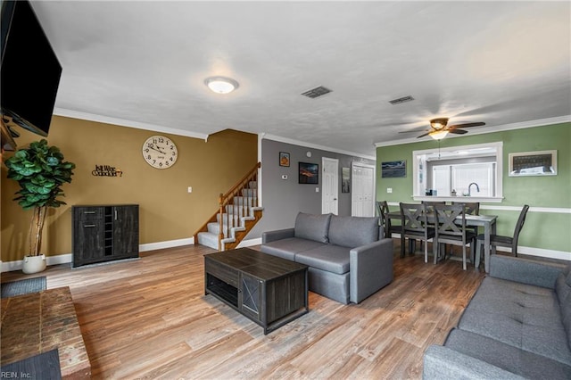 living room featuring stairway, a ceiling fan, wood finished floors, visible vents, and baseboards