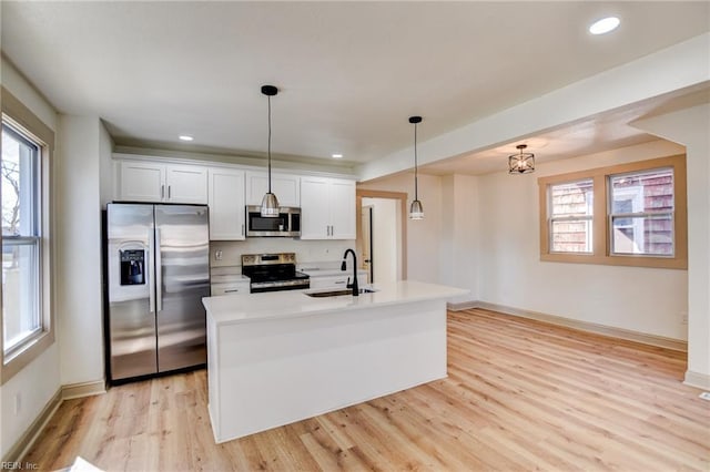 kitchen featuring light wood finished floors, a sink, light countertops, appliances with stainless steel finishes, and white cabinetry