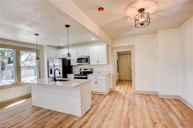 kitchen featuring appliances with stainless steel finishes, white cabinetry, light wood-type flooring, and a sink