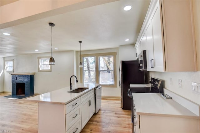 kitchen featuring light wood-style flooring, white cabinets, stainless steel appliances, and a sink