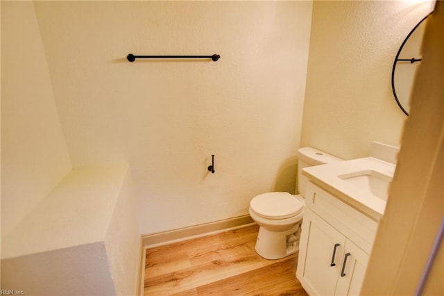 bathroom with vanity, toilet, wood finished floors, and baseboards