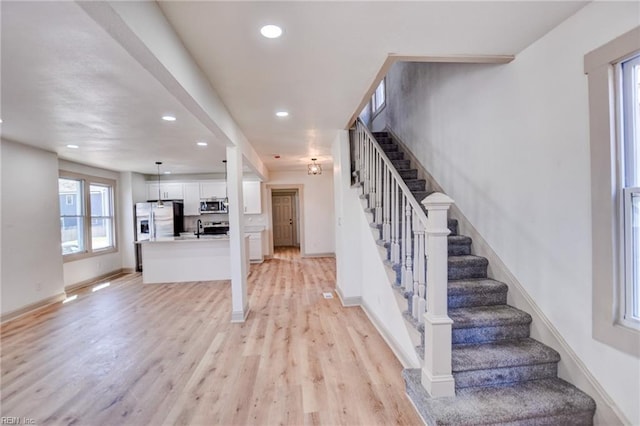 stairway featuring recessed lighting, wood finished floors, and baseboards