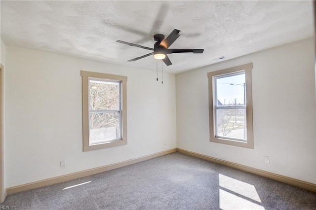 unfurnished room featuring plenty of natural light, baseboards, carpet floors, and a textured ceiling