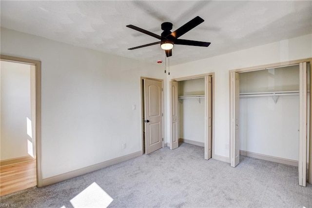 unfurnished bedroom featuring baseboards, multiple closets, a ceiling fan, and carpet flooring