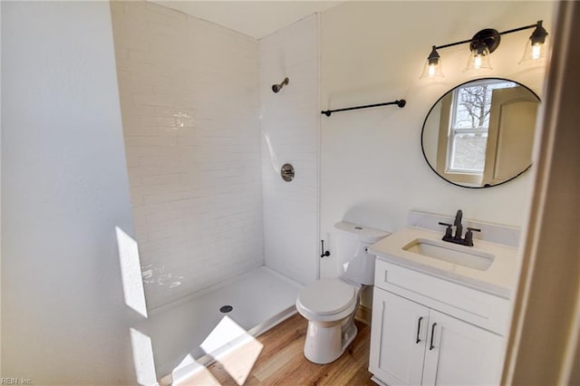 full bath with vanity, toilet, wood finished floors, and a tile shower