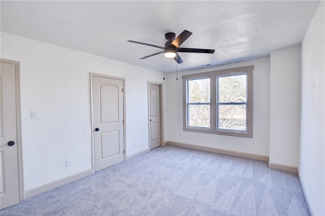 unfurnished bedroom with light colored carpet, baseboards, and ceiling fan