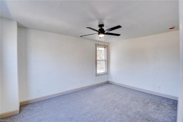 carpeted empty room with baseboards and a ceiling fan