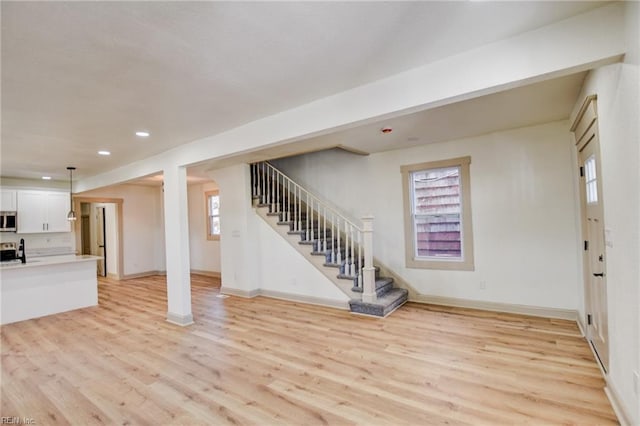 basement featuring recessed lighting, baseboards, light wood-style floors, and stairs