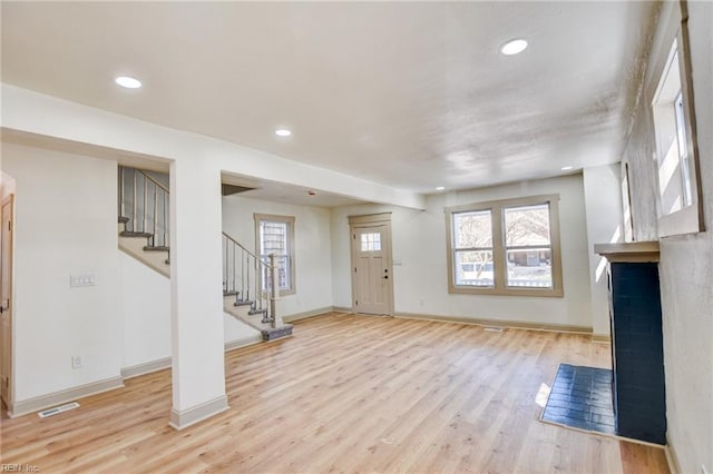 interior space featuring wood finished floors, visible vents, baseboards, stairs, and a brick fireplace