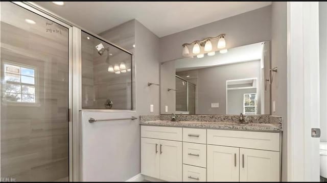 bathroom featuring a sink, a healthy amount of sunlight, a stall shower, and double vanity