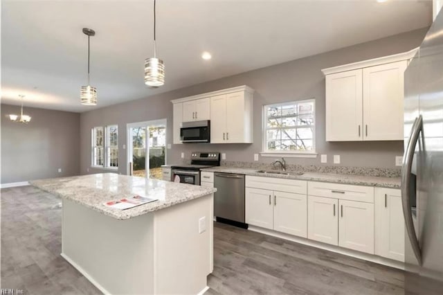 kitchen featuring stainless steel appliances, wood finished floors, white cabinets, and a center island