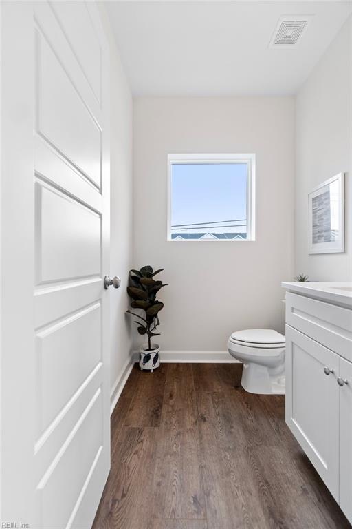 bathroom with visible vents, toilet, wood finished floors, baseboards, and vanity