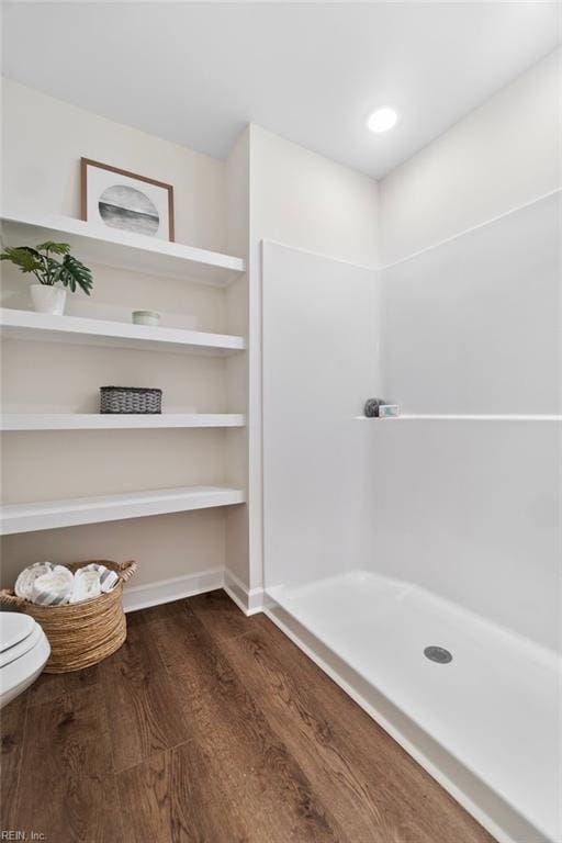 full bathroom with toilet, walk in shower, and wood finished floors