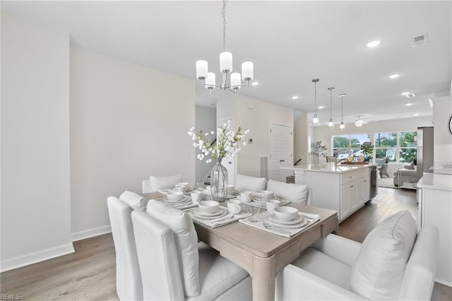 dining room with ceiling fan with notable chandelier, recessed lighting, wood finished floors, and visible vents