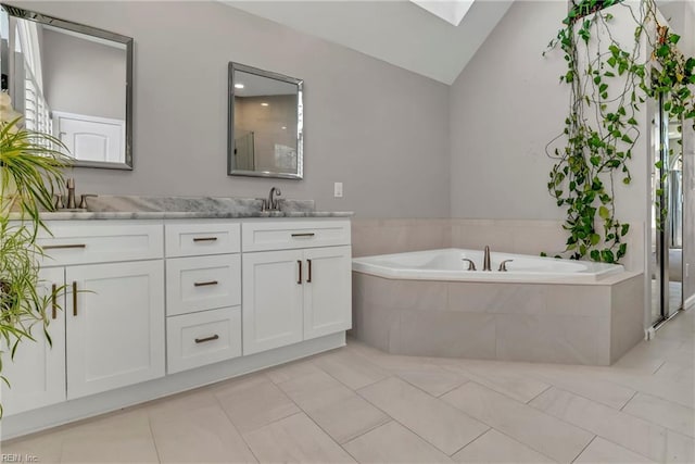 full bathroom featuring a garden tub, double vanity, vaulted ceiling with skylight, tile patterned floors, and a sink