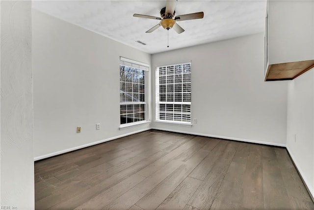 empty room with a ceiling fan, visible vents, wood finished floors, and baseboards