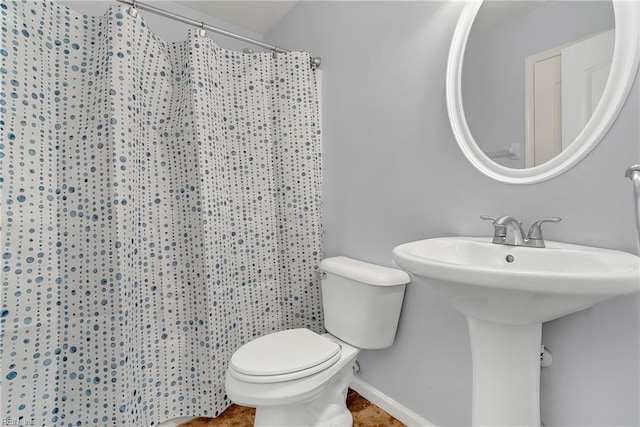 bathroom with a shower with curtain, toilet, and baseboards